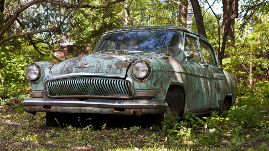 old scrap car is covered by grass